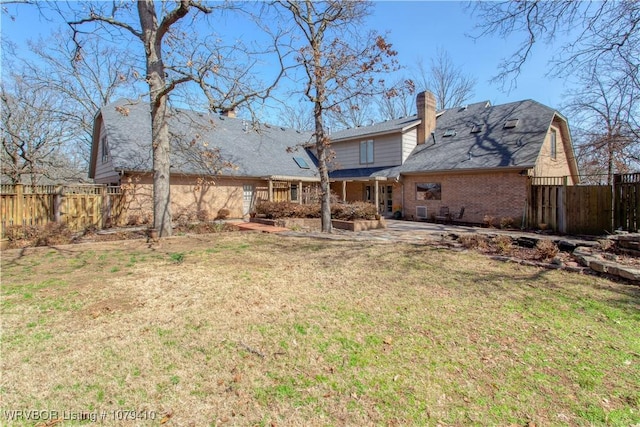 back of property with brick siding, a patio, a lawn, and fence