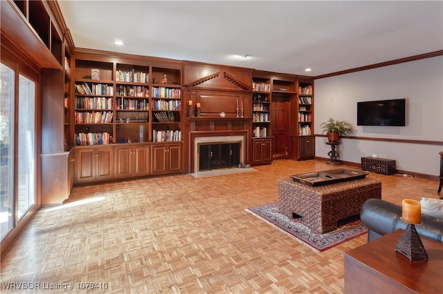 living room with built in shelves, baseboards, recessed lighting, ornamental molding, and a glass covered fireplace