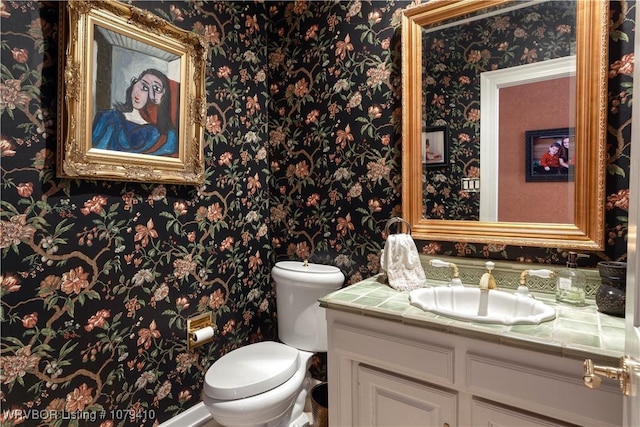 bathroom with wallpapered walls, toilet, and vanity