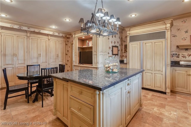 kitchen with paneled built in refrigerator, wallpapered walls, stone finish flooring, crown molding, and a center island