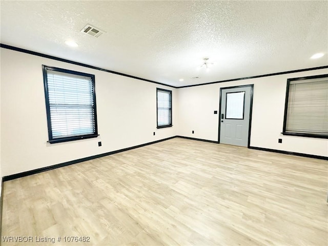 empty room with a textured ceiling, crown molding, and light hardwood / wood-style flooring