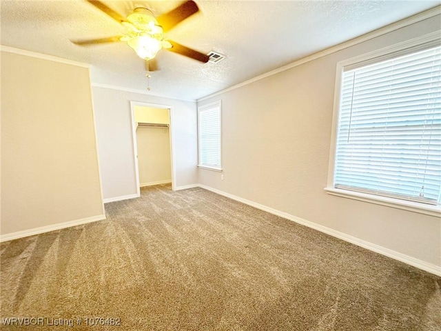 empty room featuring crown molding, plenty of natural light, carpet, and a textured ceiling