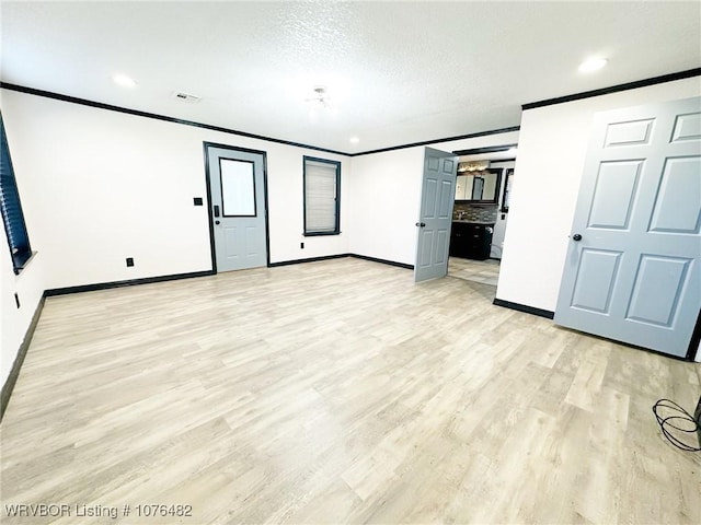 interior space with a textured ceiling, light wood-type flooring, and crown molding