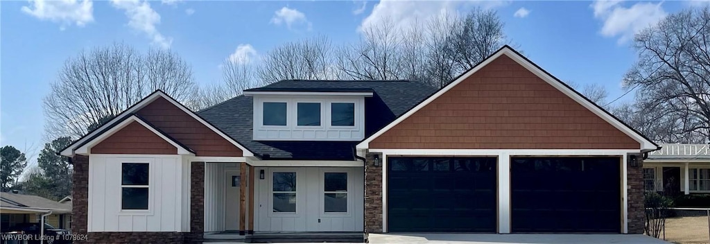 view of front of home featuring a garage, stone siding, driveway, and a shingled roof