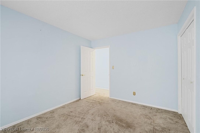 unfurnished bedroom featuring a closet and light colored carpet