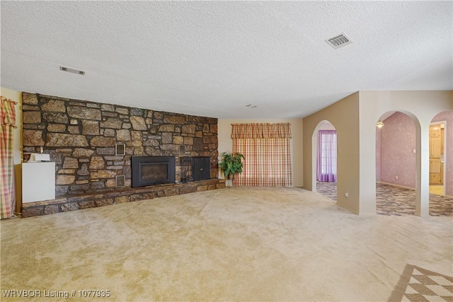 unfurnished living room featuring a stone fireplace, carpet, and a textured ceiling