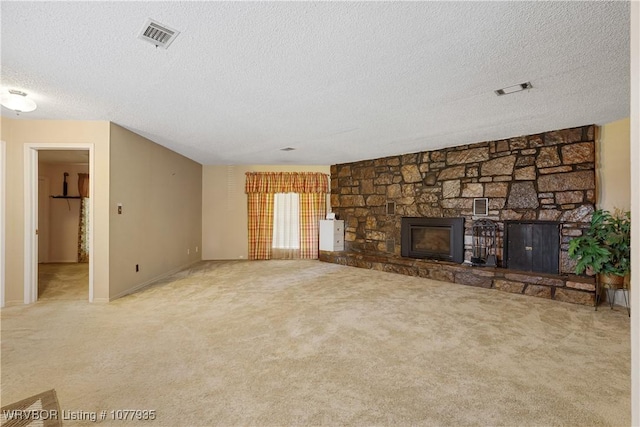 unfurnished living room featuring a stone fireplace, light colored carpet, and a textured ceiling