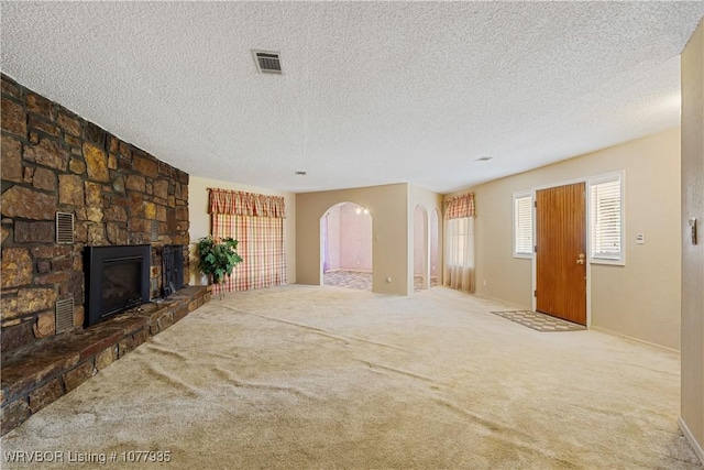 unfurnished living room with carpet flooring, a fireplace, and a textured ceiling