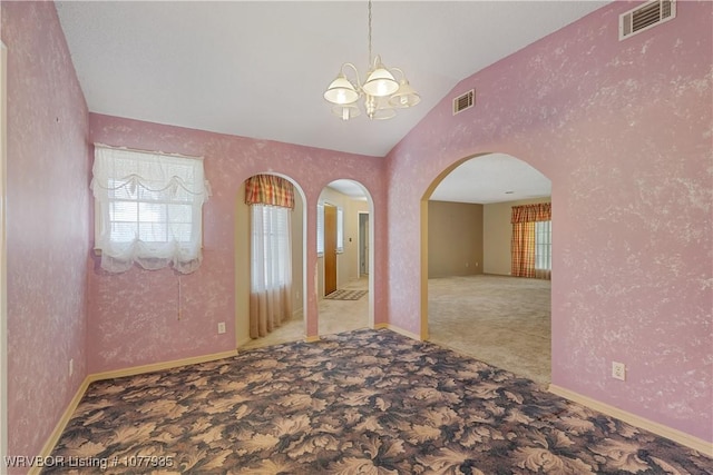 carpeted empty room with a chandelier, vaulted ceiling, and a wealth of natural light