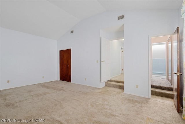 unfurnished room featuring light colored carpet and lofted ceiling