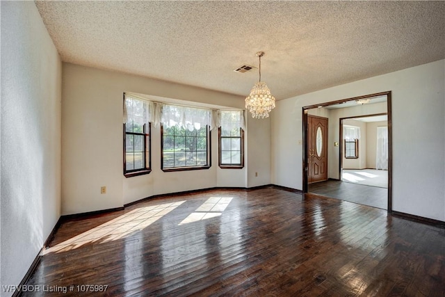 unfurnished room with wood-type flooring, a textured ceiling, and a chandelier