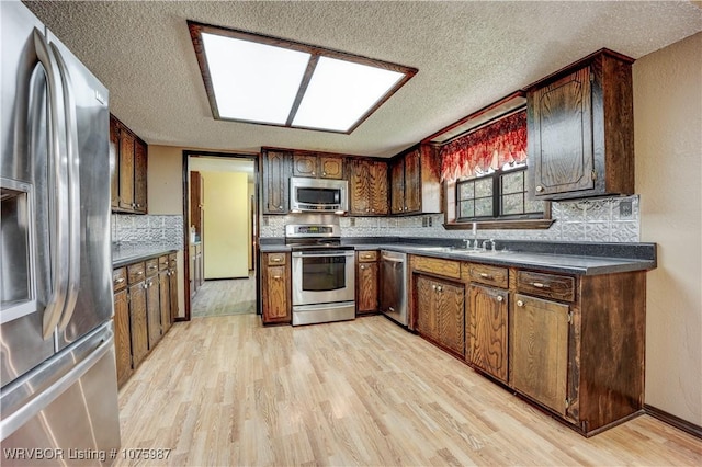 kitchen featuring light hardwood / wood-style flooring, stainless steel appliances, a textured ceiling, and sink