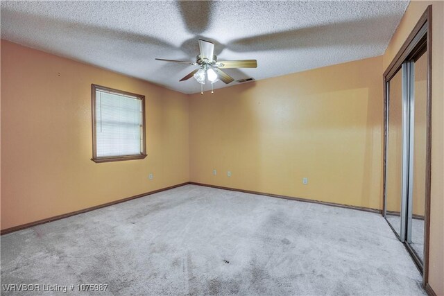 unfurnished bedroom featuring light carpet, a textured ceiling, and ceiling fan