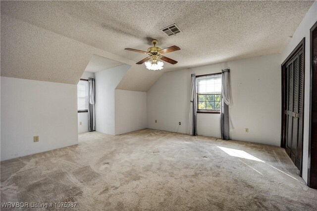 bonus room featuring ceiling fan, light colored carpet, lofted ceiling, and a textured ceiling