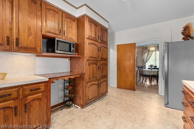 2055 Barber Rd, Booneville, AR 72927 - kitchen with appliances with stainless steel finishes, brown cabinets, light floors, decorative backsplash, and light countertops