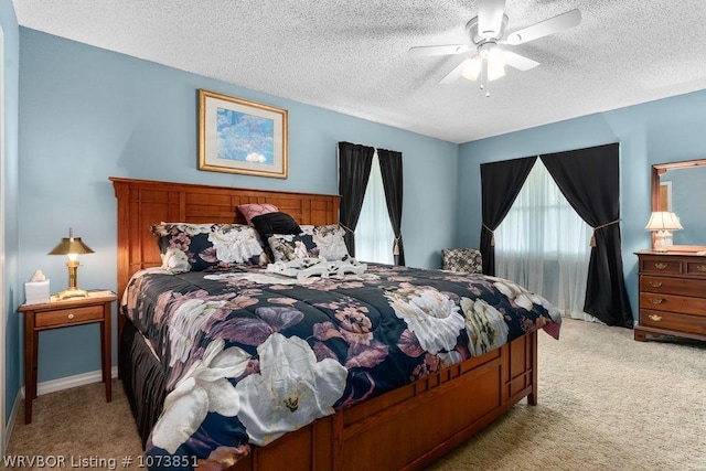 bedroom with ceiling fan, light colored carpet, and a textured ceiling