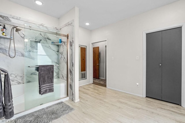 bathroom with hardwood / wood-style flooring and a shower with door