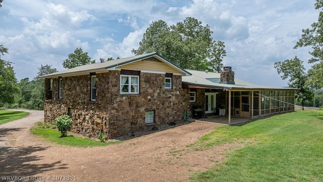 2055 Barber Rd, Booneville, AR 72927 - rear view of house featuring stone siding, a chimney, a sunroom, a yard, and a metal roof