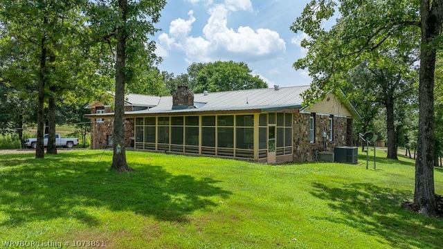 rear view of property with a yard, a sunroom, and central air condition unit