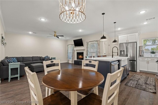 8323 Mclaren Dr, Fort Smith, AR 72916 - dining area featuring dark wood finished floors, a lit fireplace, recessed lighting, ceiling fan, and a chandelier