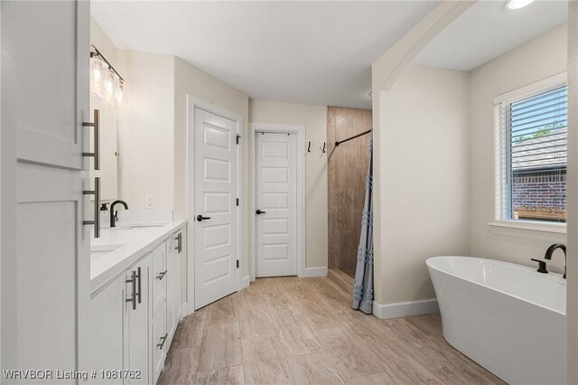 8323 Mclaren Dr, Fort Smith, AR 72916 - bathroom featuring double vanity, a shower stall, a freestanding tub, and wood finished floors