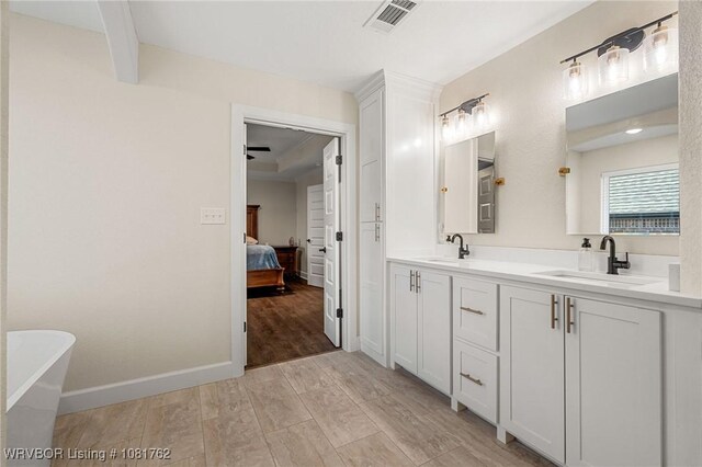 8323 Mclaren Dr, Fort Smith, AR 72916 - full bathroom featuring double vanity, a freestanding tub, connected bathroom, and wood finished floors