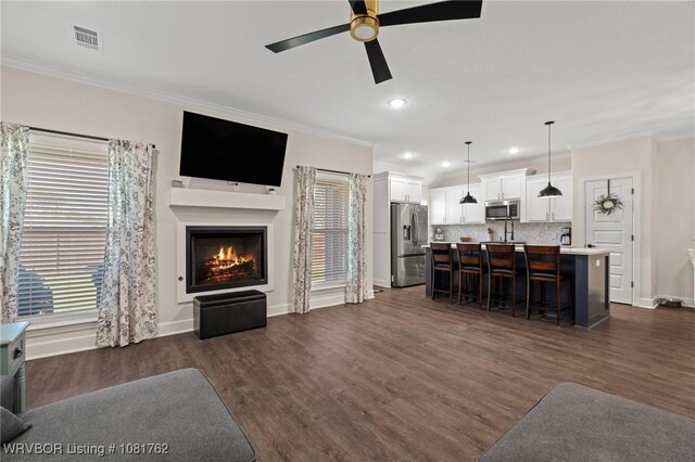 8323 Mclaren Dr, Fort Smith, AR 72916 - living area with ornamental molding, ceiling fan, a warm lit fireplace, dark wood-style flooring, and recessed lighting