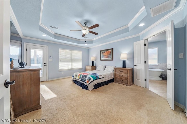 carpeted bedroom featuring ceiling fan, ensuite bathroom, multiple windows, and a tray ceiling