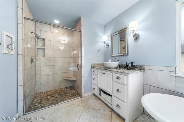 bathroom featuring tile patterned floors, vanity, tile walls, and independent shower and bath