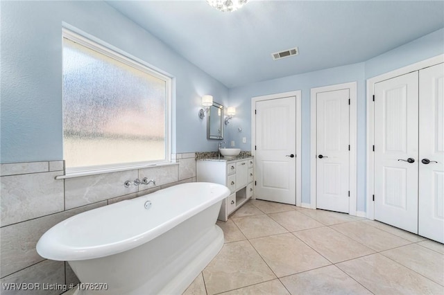 bathroom featuring a bathing tub, vanity, tile walls, and tile patterned flooring