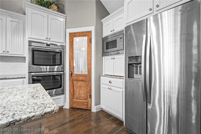 kitchen with light stone countertops, stainless steel appliances, white cabinetry, and tasteful backsplash