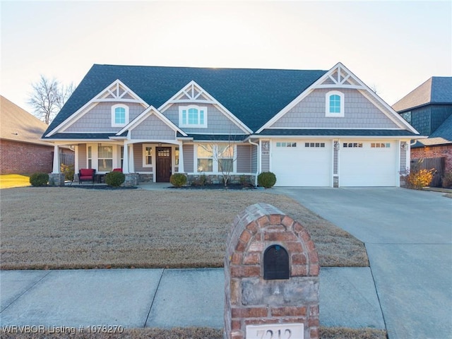 craftsman inspired home with covered porch, a garage, and a front lawn