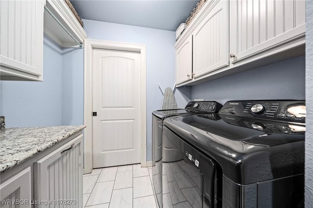 clothes washing area featuring cabinets and washing machine and dryer