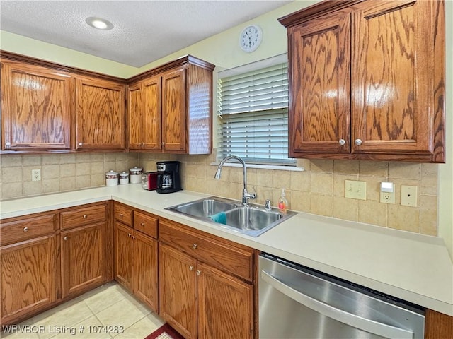 kitchen featuring sink, stainless steel dishwasher, backsplash, a textured ceiling, and light tile patterned flooring