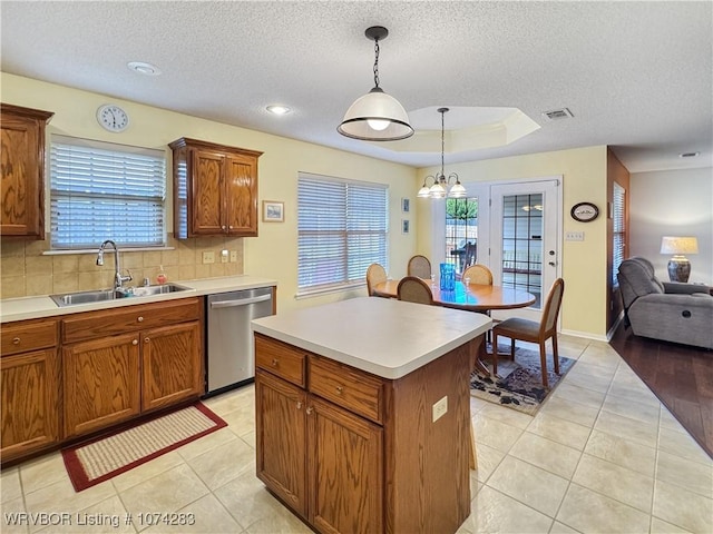 kitchen featuring a center island, sink, stainless steel dishwasher, tasteful backsplash, and decorative light fixtures