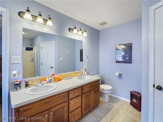 bathroom featuring vanity, a shower, tile patterned flooring, toilet, and a textured ceiling