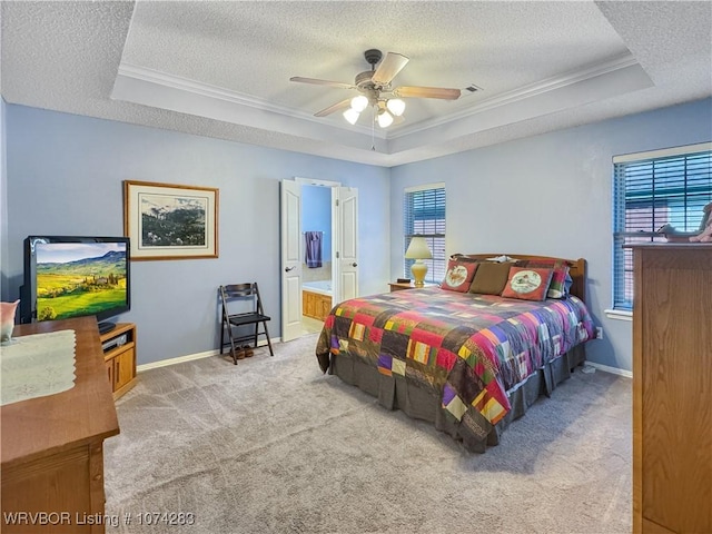 carpeted bedroom featuring multiple windows, connected bathroom, a raised ceiling, and ceiling fan