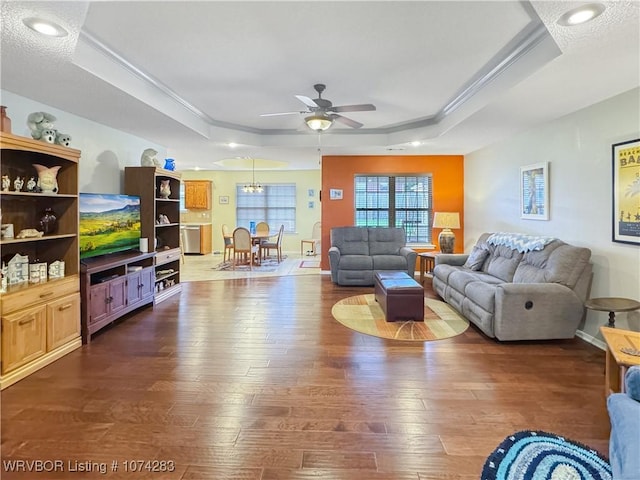 living room featuring a raised ceiling, ceiling fan, dark wood-type flooring, and a textured ceiling