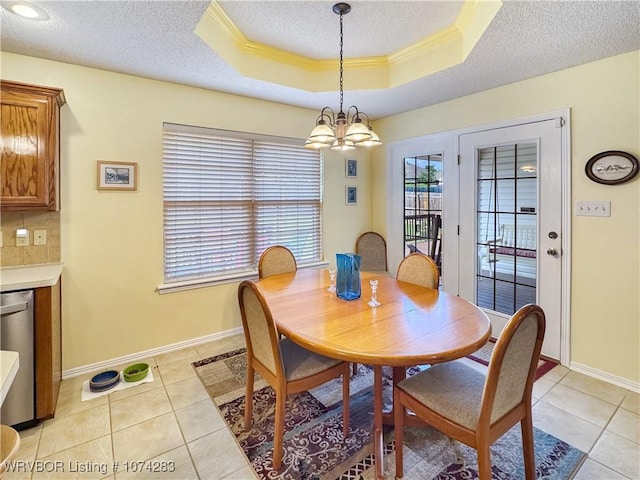 tiled dining space with a textured ceiling, an inviting chandelier, a raised ceiling, and ornamental molding