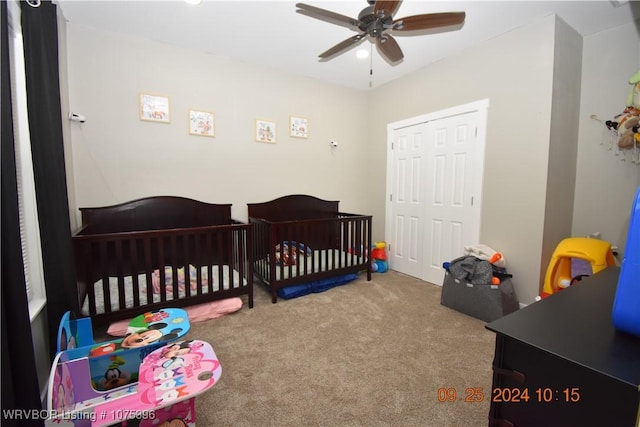 carpeted bedroom with ceiling fan and a nursery area