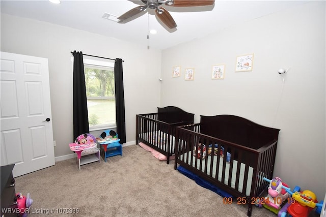 bedroom with ceiling fan, a nursery area, and light carpet