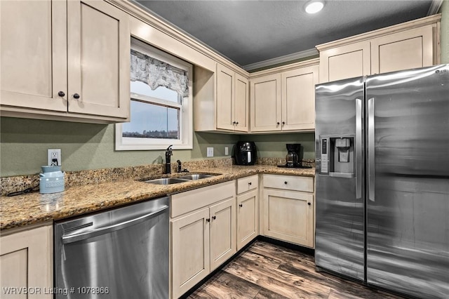 kitchen featuring dark hardwood / wood-style floors, sink, light stone counters, stainless steel appliances, and cream cabinetry