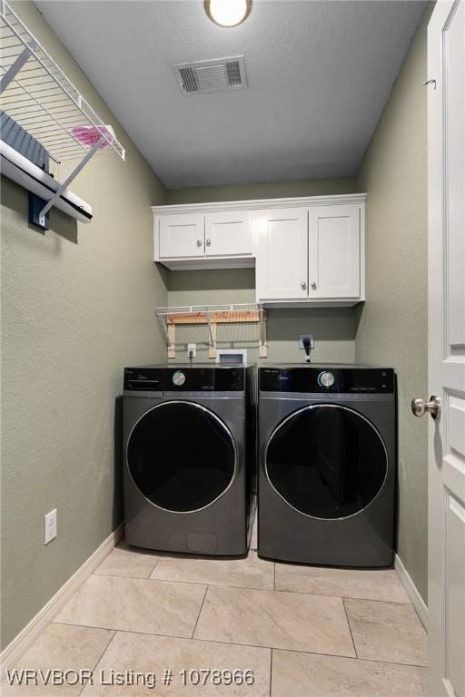 laundry room featuring cabinets, light tile patterned floors, and washing machine and clothes dryer