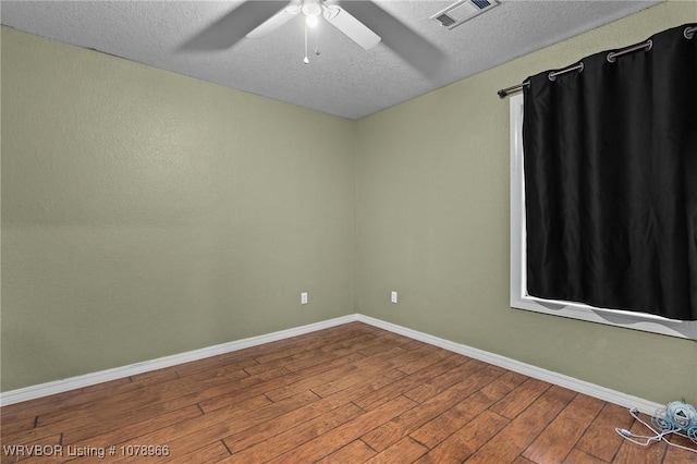 empty room with ceiling fan, wood-type flooring, and a textured ceiling