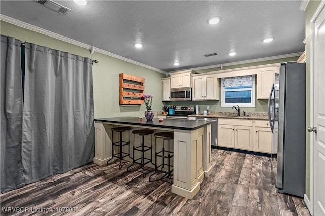 kitchen with sink, crown molding, stainless steel appliances, a kitchen bar, and kitchen peninsula