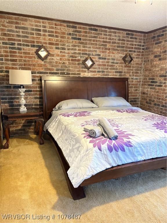 bedroom with brick wall, light carpet, and a textured ceiling