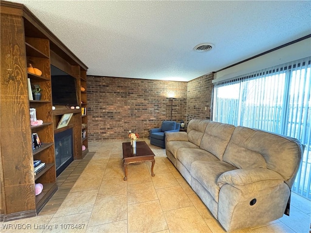 tiled living room with a textured ceiling and brick wall