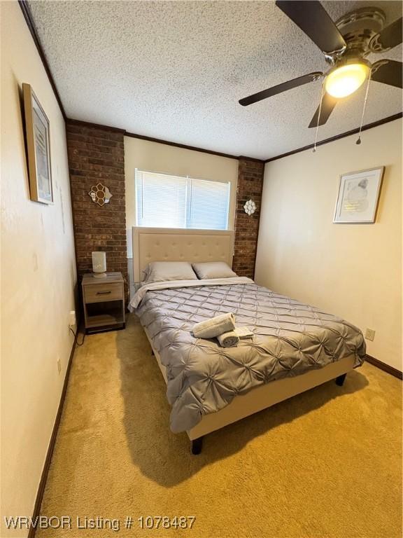 carpeted bedroom with ceiling fan, ornamental molding, and a textured ceiling