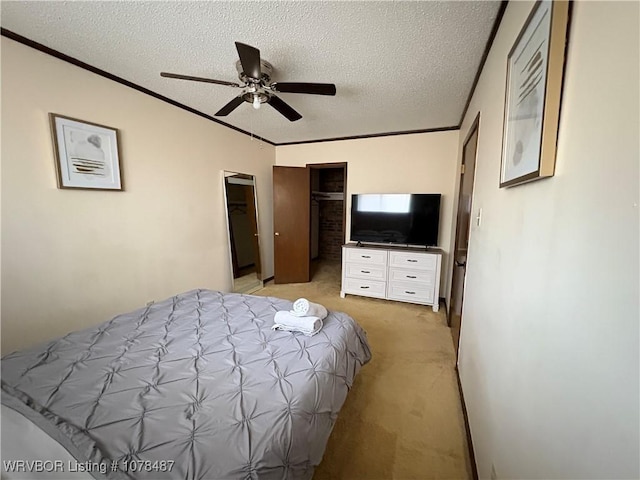 bedroom with a walk in closet, crown molding, light carpet, a textured ceiling, and a closet