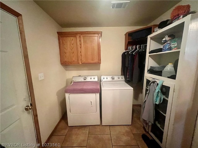 clothes washing area with cabinets, light tile patterned floors, and washer and dryer